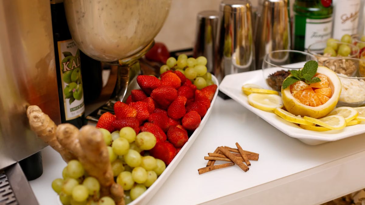 Vibrant still-life of strawberries, grapes, citrus slices, and herbs on a bar counter.
